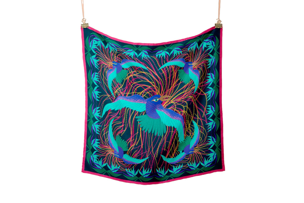 full view of a dark green silk foulard named les oiseaux de paradis with yellow and pink decorative elements and birds