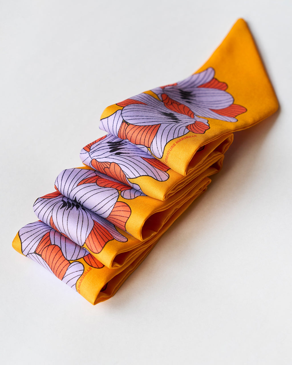 silk twilly flor jaune soleil with purple and orange flowers folded neatly