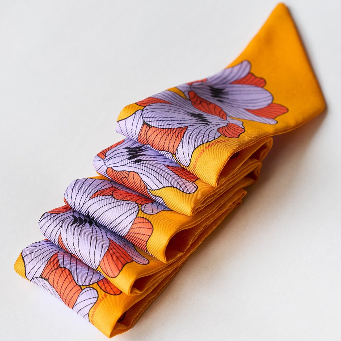 silk twilly flor jaune soleil with purple and orange flowers folded neatly